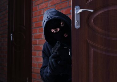 Kapalı kapılar ardında silah gözetleyen maskeli adam. Suç