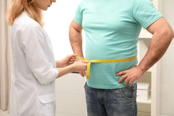 Médico midiendo la cintura del hombre con sobrepeso en el hospital, primer plano — Foto de Stock