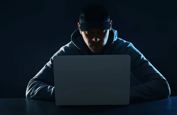 Человек, использующий ноутбук за столом на тёмном фоне. Криминальная деятельность — стоковое фото