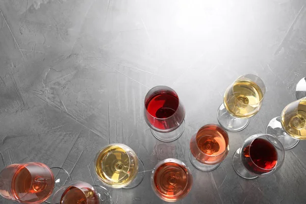 Diferentes copos com vinho no fundo cinza, flat lay. espaço para texto — Fotografia de Stock