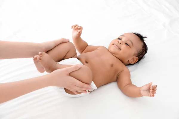 Anne ve tatlı çocuğu beyaz yatakta. Bebek masajı ve egzersizler. — Stok fotoğraf