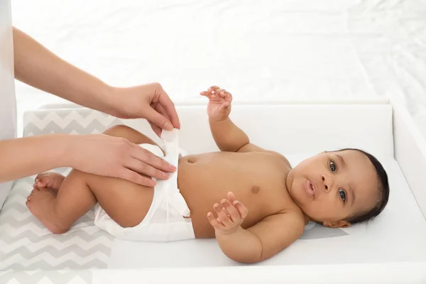 Mother changing her baby's diaper on table indoors — Stock Photo, Image