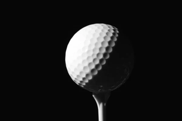 Pallina da golf su tee contro sfondo scuro — Foto Stock