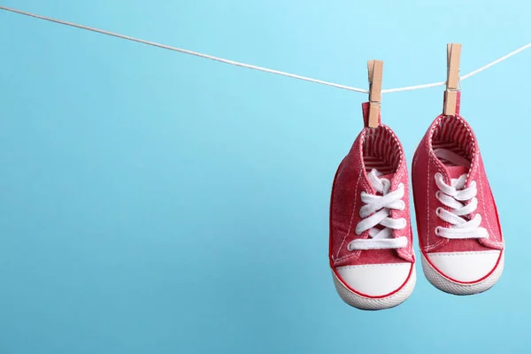 Χαριτωμένα μικρά παπούτσια κρέμονται στο πλύσιμο γραμμή από το χρώμα φόντο, Χώρος για το κείμενο. Βρεφικά αξεσουάρ — Φωτογραφία Αρχείου
