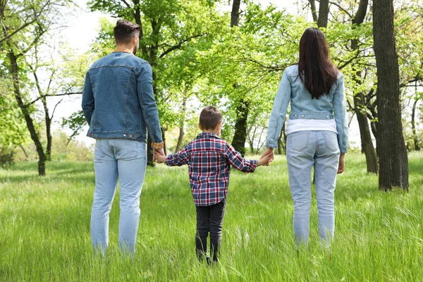 Niño pequeño cogido de la mano con sus padres en el parque. Tiempo en familia — Foto de Stock