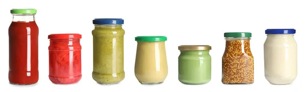 Conjunto de frascos de vidro com diferentes molhos deliciosos no fundo branco — Fotografia de Stock