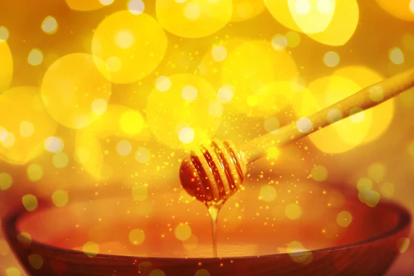 Miel goteando desde el cazo en un tazón contra luces borrosas, primer plano — Foto de Stock