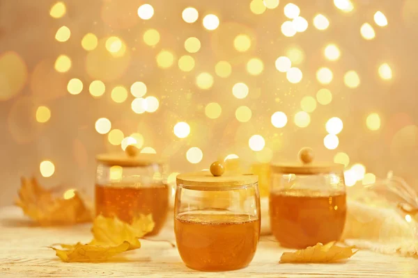 Γυάλινα βάζα με το γλυκό μέλι στο τραπέζι ενάντια σε θολά φώτα. Χώρο για το κείμενο — Φωτογραφία Αρχείου