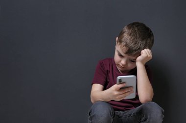 Siyah arka plan üzerinde cep telefonu ile Üzgün küçük çocuk, metin için alan