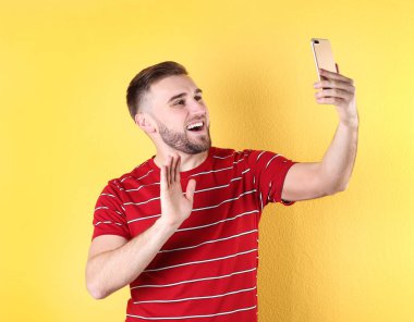 Renkli arka plan karşı Smartphone video sohbet kullanarak genç adam
