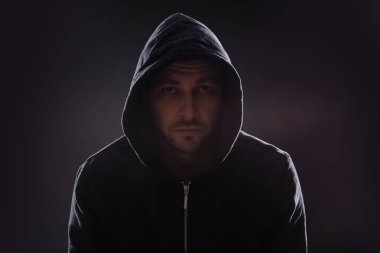 Karanlık arka planda kapüşonlu gizemli adam. Tehlikeli suçlu