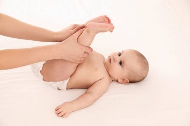 Anne ve tatlı çocuğu beyaz yatakta. Bebek masajı ve egzersizler.