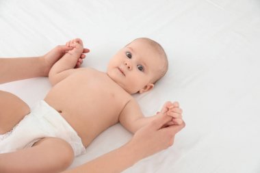 Anne ve beyaz yatakta onun sevimli çocuk, metin için alan. Bebek masajı ve egzersizleri