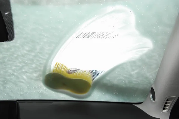 Worker cleaning automobile windshield with sponge at car wash, view from inside — Stock Photo, Image