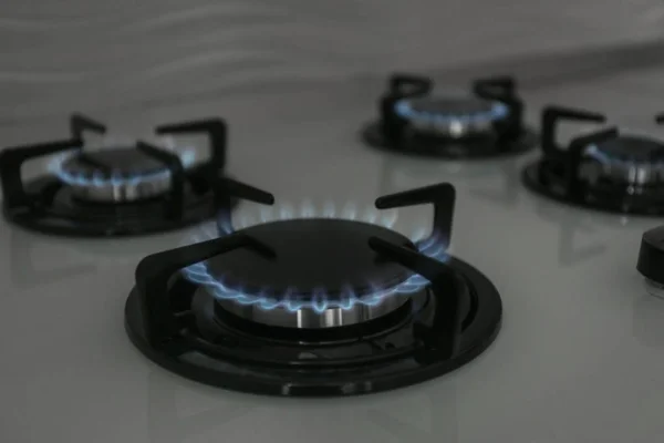 Gas burners with blue flame on modern stove. Space for text — Stock Photo, Image