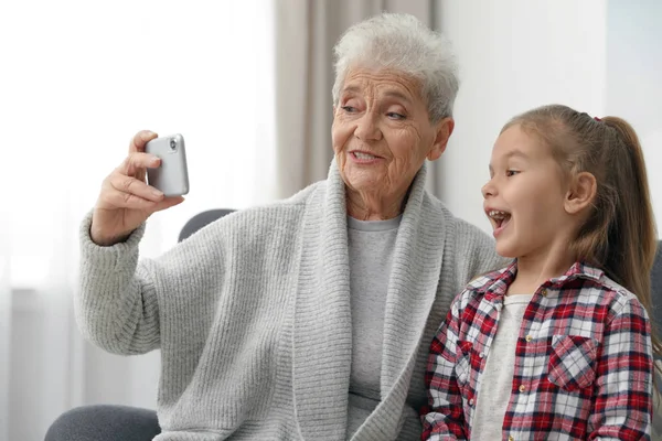 Süßes Mädchen und ihre Großmutter beim Selfie zu Hause — Stockfoto