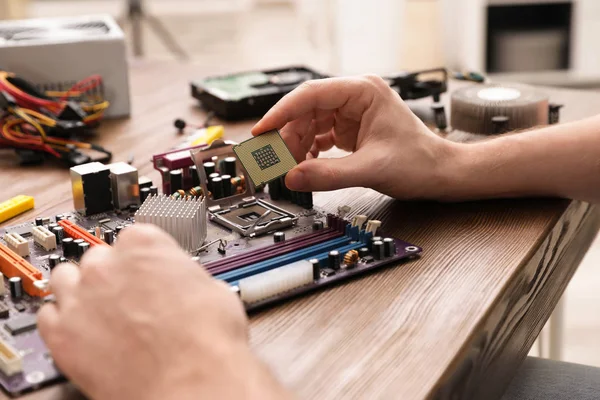 Male technician repairing motherboard at table, closeup