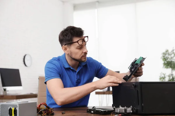 Técnico masculino reparando computador na mesa dentro de casa — Fotografia de Stock