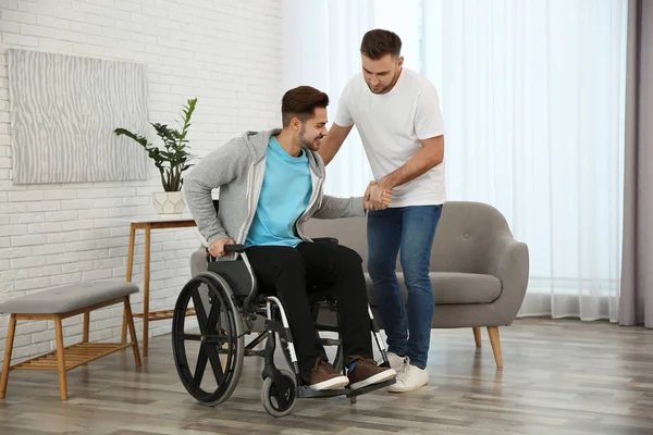 Wolontariusz pomagający człowiekowi na wózku inwalidzkim w domu — Zdjęcie stockowe