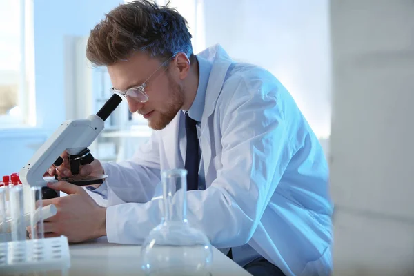 Homme scientifique utilisant un microscope moderne en laboratoire de chimie — Photo