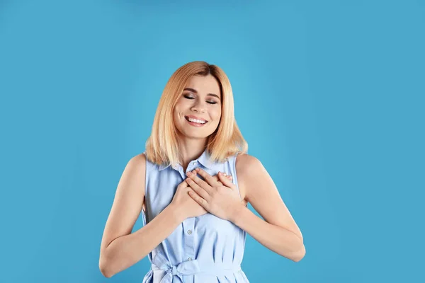 Retrato de mujer cogida de la mano cerca del corazón sobre fondo de color — Foto de Stock