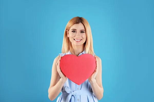 Mooie vrouw met hartvormige doos op kleur achtergrond — Stockfoto