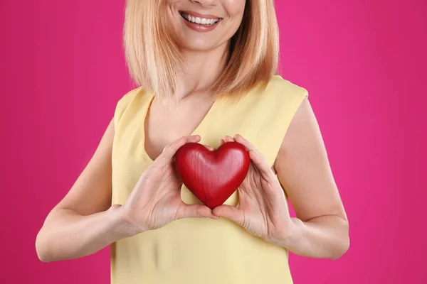 Vrouw met decoratieve hart op kleur achtergrond, close-up — Stockfoto
