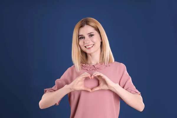 Portret van vrouw maken hart met haar handen op een achtergrond met kleur — Stockfoto