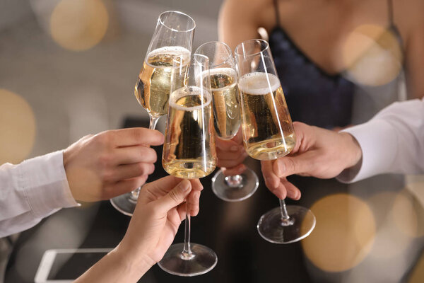 Friends clinking glasses of champagne in restaurant, closeup