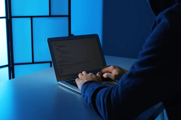 Man using laptop at table in dark room, closeup. Criminal offence — Stock Photo, Image