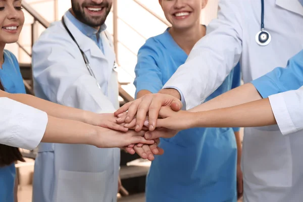 Equipo de médicos poniendo las manos juntas en el interior, primer plano. Concepto de unidad — Foto de Stock