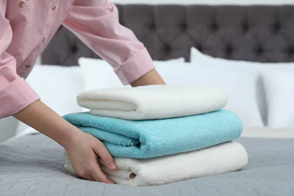 Женщина кладет стопку чистых полотенец на кровать — стоковое фото