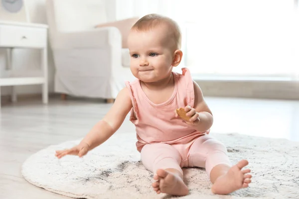 Niedliches kleines Mädchen mit Keksen auf dem Fußboden im Zimmer — Stockfoto