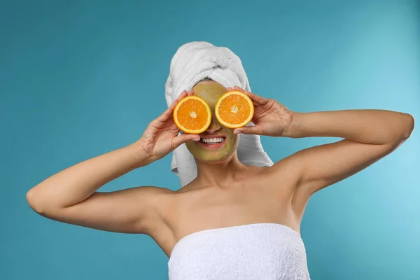 Mooie vrouw met masker op gezicht en gesneden Oranje tegen kleur achtergrond — Stockfoto