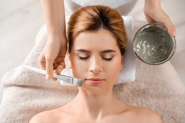 Cosmetologo applicare maschera sul viso della donna nel salone spa, vista dall'alto — Foto Stock