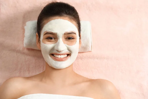 Beautiful woman with white mask on face relaxing in spa salon, top view — Stock Photo, Image