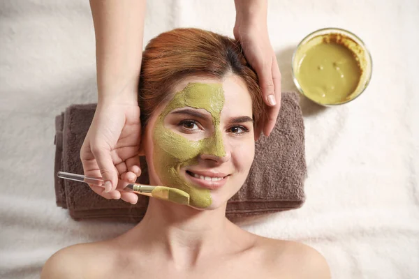 Kosmetologis menerapkan topeng ke wajah wanita di spa salon, pandangan atas — Stok Foto