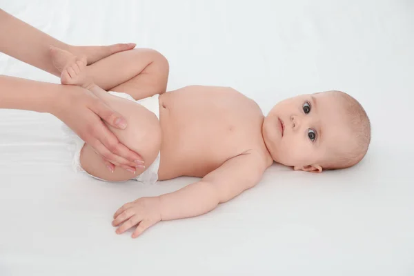 Moeder en haar schattige kind op wit bed. Baby massage en oefeningen — Stockfoto