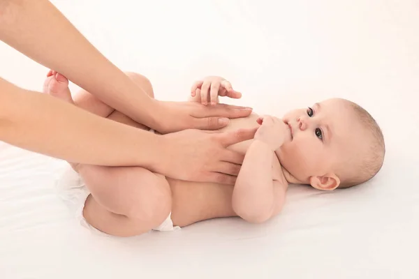 Mutter und ihr süßes Kind auf weißem Bett. Babymassage und Übungen — Stockfoto