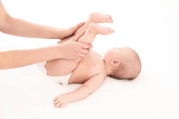 Mor och hennes söta barn på vit säng. Babymassage och övningar — Stockfoto