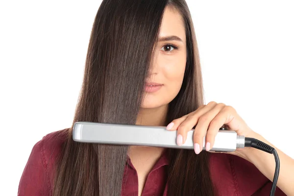 Jovem mulher usando ferro de cabelo no fundo branco — Fotografia de Stock