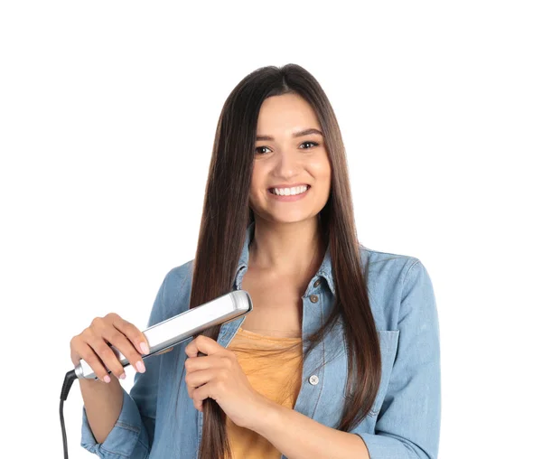 Молодая женщина использует утюг для волос на белом фоне — стоковое фото