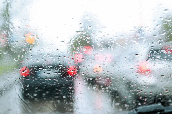 Blurred view of road through wet car window. Rainy weather — Stock Photo, Image