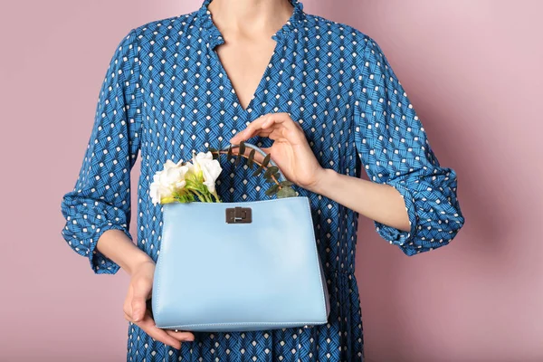 Mulher elegante com bolsa e flores de primavera contra fundo de cor, close-up — Fotografia de Stock