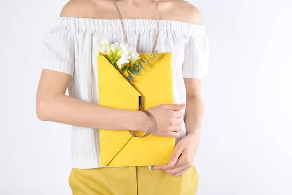 Mujer con estilo con embrague y flores de primavera sobre fondo claro, primer plano —  Fotos de Stock