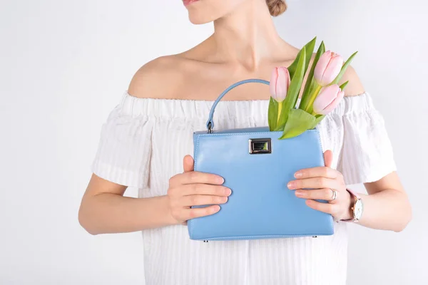 Mulher elegante com bolsa e flores de primavera contra fundo leve, close-up — Fotografia de Stock