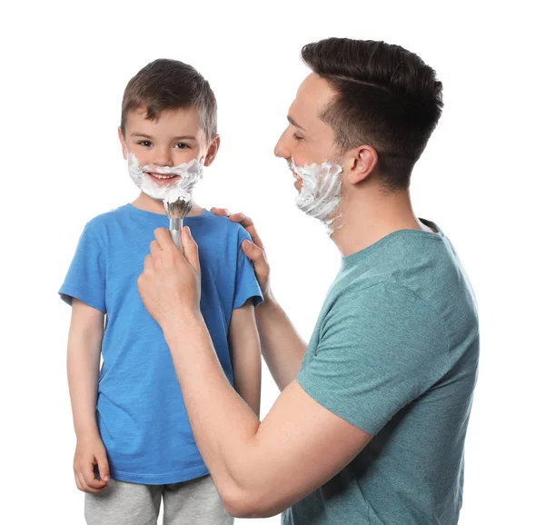 Vader scheerschuim aanbrengen op het gezicht van zoon tegen witte achtergrond — Stockfoto