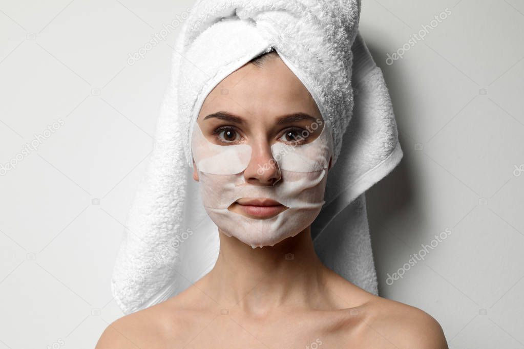 Beautiful woman with cotton face and eye masks against light background