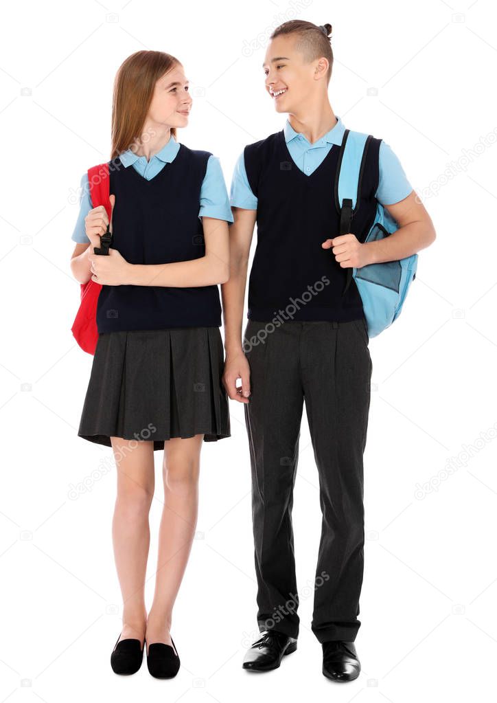 Full length portrait of teenagers in school uniform with backpacks on white background