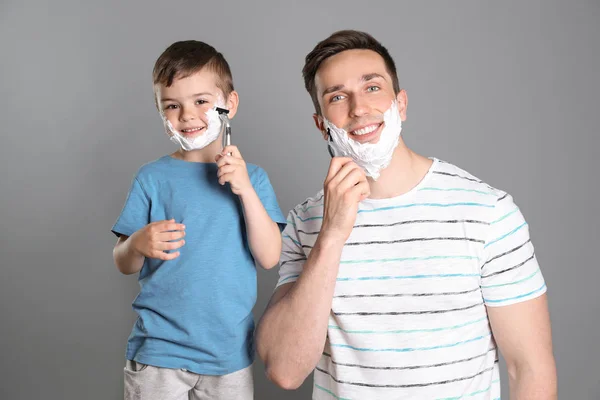 Papa scheren en kleine zoon imiteren hem op kleur achtergrond — Stockfoto
